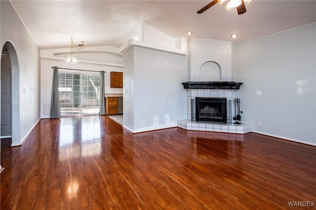 unfurnished living room featuring dark wood finished floors, lofted ceiling, ceiling fan with notable chandelier, and arched walkways