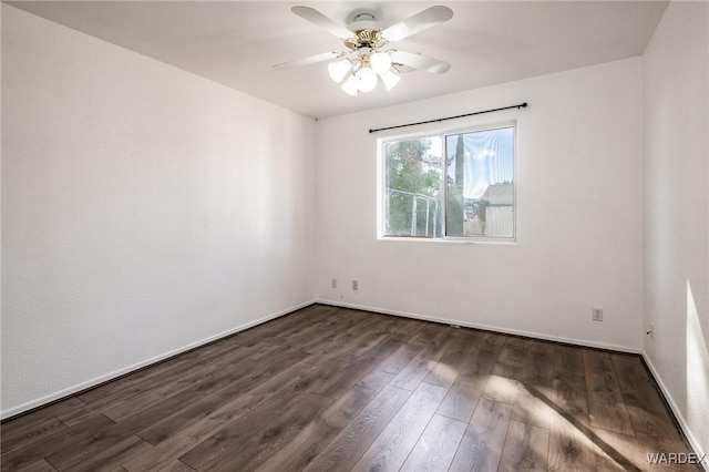 unfurnished room featuring dark wood-type flooring, a ceiling fan, and baseboards