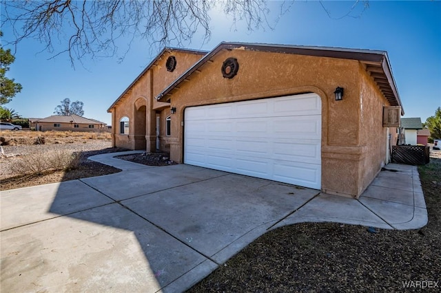 view of front of house featuring concrete driveway, an attached garage, and stucco siding