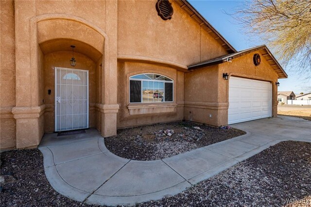 doorway to property with concrete driveway, a garage, and stucco siding