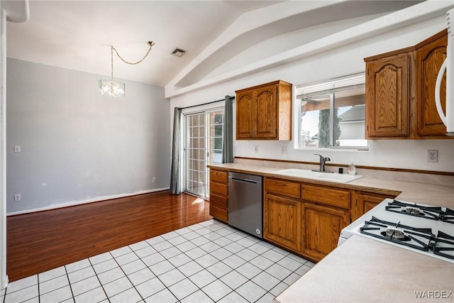 kitchen with stainless steel dishwasher, light countertops, lofted ceiling, and a sink