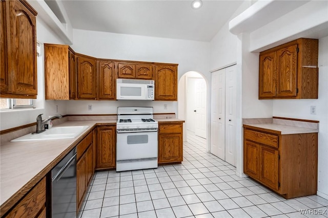 kitchen with white appliances, brown cabinetry, light countertops, and a sink