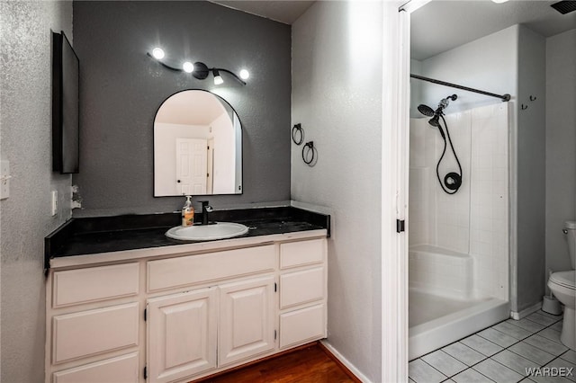 bathroom with a shower, baseboards, toilet, and vanity