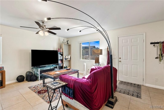 living area featuring a ceiling fan, baseboards, and light tile patterned floors