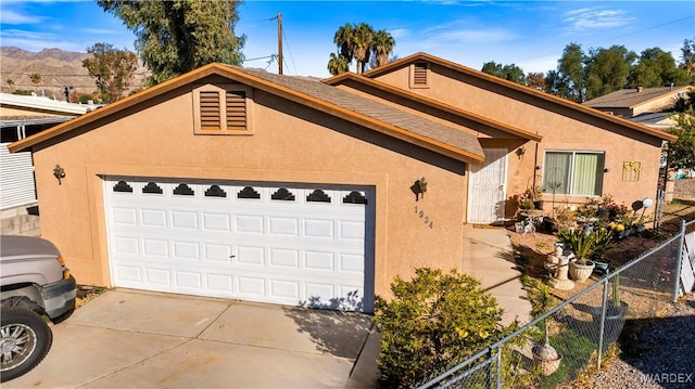 view of front of home with an outbuilding, a garage, fence, concrete driveway, and stucco siding