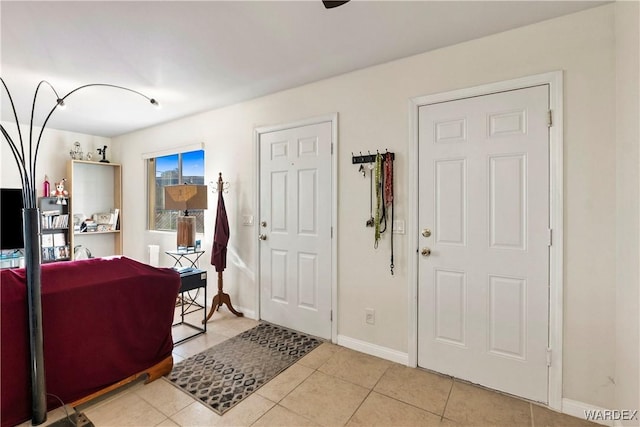 foyer entrance featuring light tile patterned flooring and baseboards