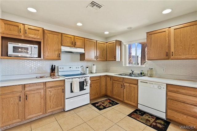 kitchen with under cabinet range hood, white appliances, a sink, visible vents, and light countertops