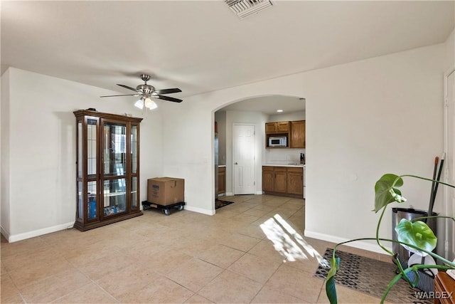 interior space featuring a ceiling fan, arched walkways, visible vents, and baseboards