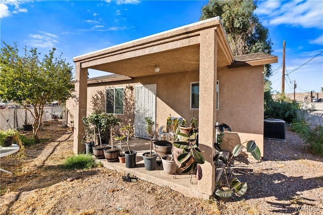 rear view of house with central air condition unit, fence, and stucco siding