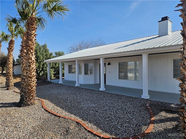 exterior space with a chimney, metal roof, and a porch