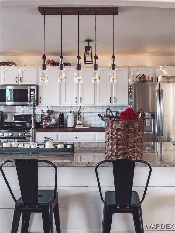 kitchen with stainless steel appliances, white cabinets, and decorative backsplash