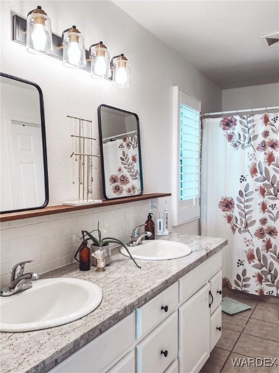 full bathroom featuring double vanity, tile patterned floors, a sink, and decorative backsplash