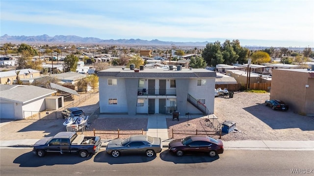 view of front of property featuring a residential view, fence, a mountain view, and stucco siding