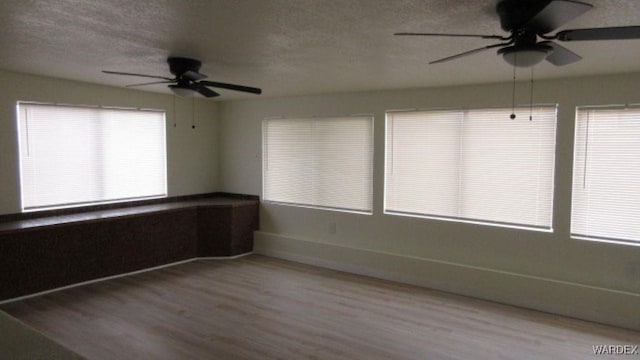 unfurnished room featuring a textured ceiling, wood finished floors, and a ceiling fan