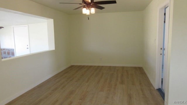 empty room featuring baseboards, wood finished floors, and a ceiling fan