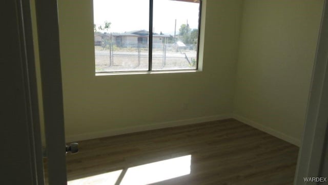 spare room featuring dark wood-style floors and baseboards