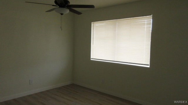 spare room with baseboards, wood finished floors, and ceiling fan