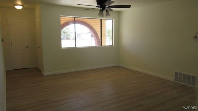 spare room with a ceiling fan, wood finished floors, baseboards, and visible vents