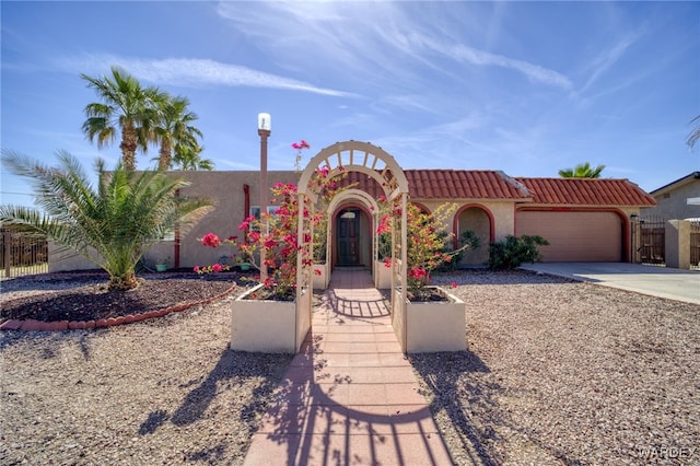 view of front of house with stucco siding, concrete driveway, fence, a garage, and a tiled roof