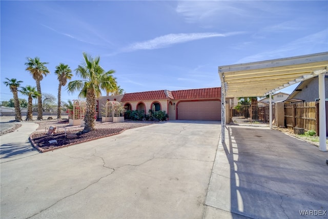 mediterranean / spanish-style house with a tile roof, stucco siding, an attached garage, fence, and driveway