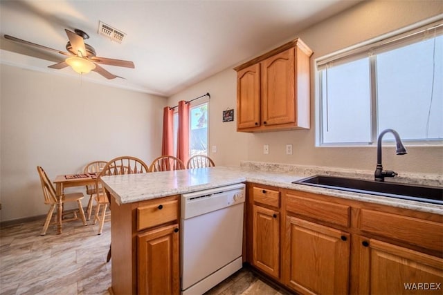 kitchen with visible vents, a peninsula, white dishwasher, light countertops, and a sink