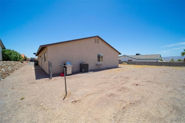 view of side of property featuring fence, cooling unit, and stucco siding