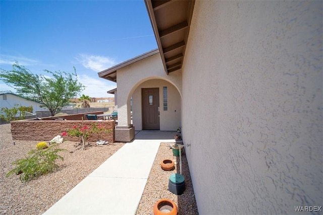 doorway to property with fence and stucco siding