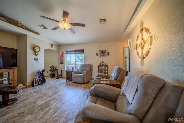 living room with visible vents, arched walkways, and a ceiling fan