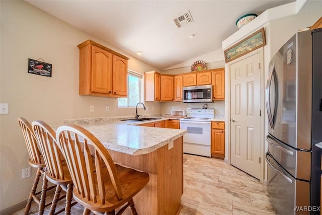 kitchen featuring stainless steel appliances, light countertops, visible vents, a sink, and a kitchen bar