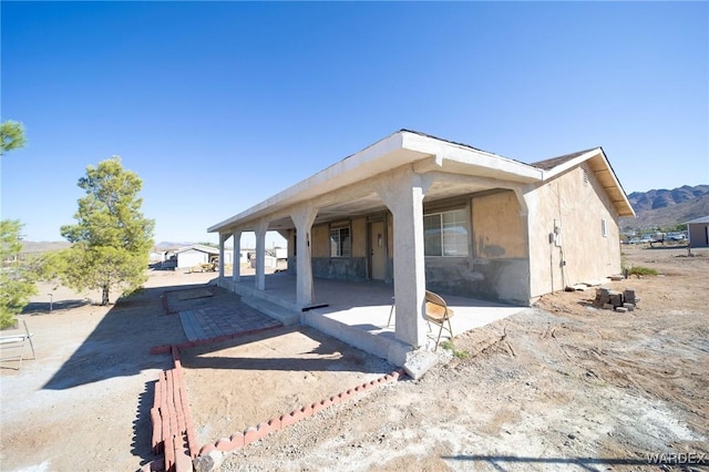 view of side of home featuring a patio, a mountain view, and stucco siding