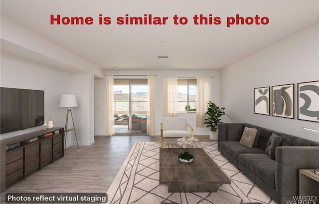 living room featuring light wood-type flooring, visible vents, and baseboards