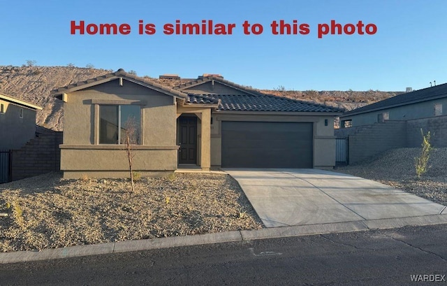 view of front of home with a tile roof, stucco siding, concrete driveway, an attached garage, and fence