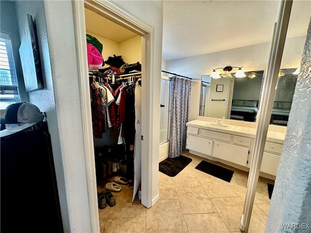 full bathroom with a spacious closet, tile patterned flooring, shower / bath combo with shower curtain, and vanity