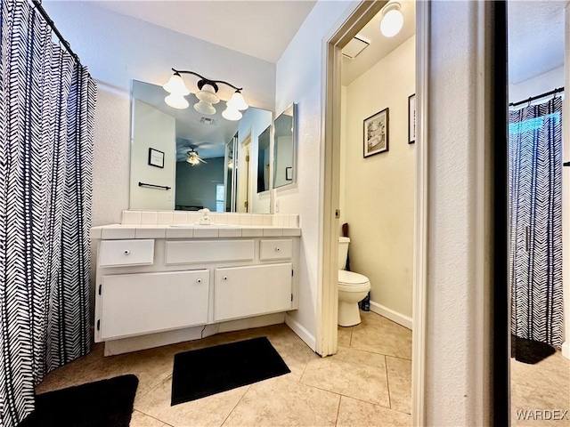 bathroom with baseboards, toilet, ceiling fan, tile patterned flooring, and vanity