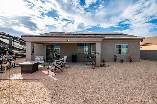 back of property with solar panels, a patio area, fence, and stucco siding