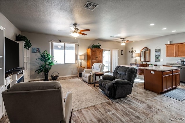 living room featuring a textured ceiling, ceiling fan, recessed lighting, visible vents, and light wood-style floors