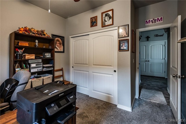 office area featuring ceiling fan, dark colored carpet, and baseboards