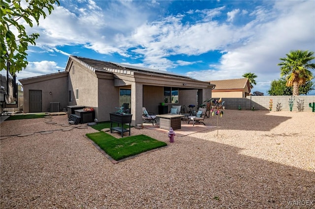 back of house featuring a patio, an outdoor fire pit, central AC unit, a fenced backyard, and stucco siding