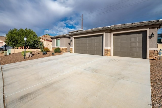 view of front of property with stucco siding, a garage, stone siding, driveway, and a tiled roof