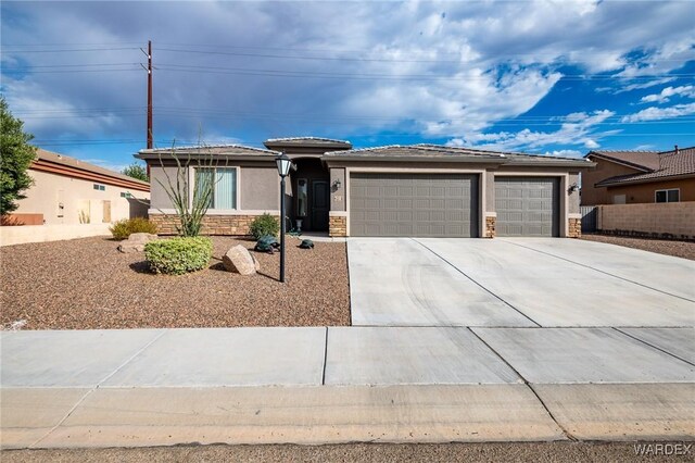 prairie-style house featuring a garage, stone siding, concrete driveway, and stucco siding