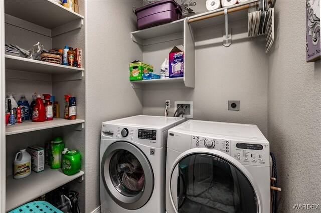 laundry area featuring laundry area, a textured wall, and washer and clothes dryer