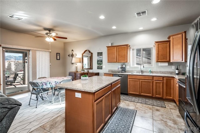 kitchen with visible vents, brown cabinetry, a kitchen island, appliances with stainless steel finishes, and a sink