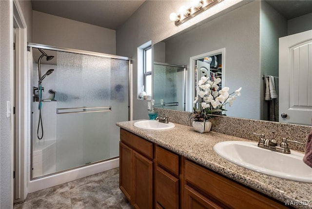 bathroom featuring double vanity, a shower stall, and a sink