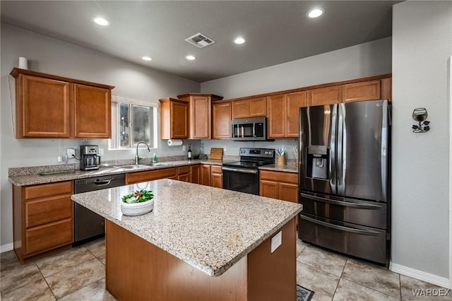 kitchen with stainless steel appliances, a sink, a kitchen island, visible vents, and light stone countertops