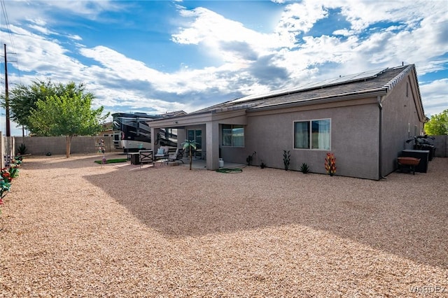 rear view of property with solar panels, a patio, a fenced backyard, and stucco siding