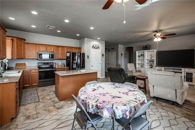 kitchen with a center island, brown cabinets, appliances with stainless steel finishes, open floor plan, and a sink