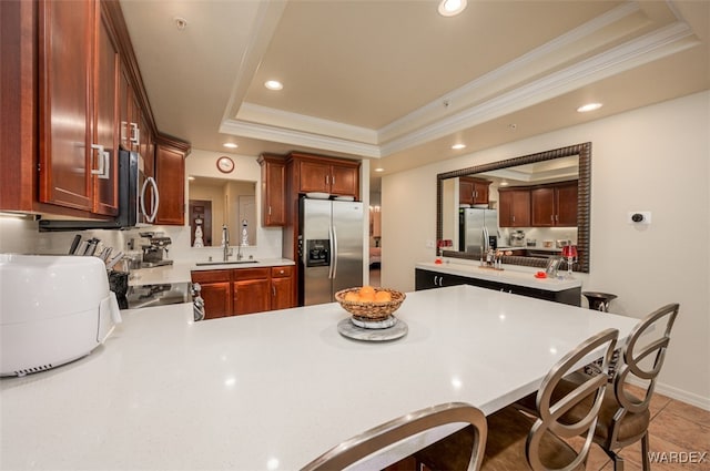 kitchen featuring visible vents, a sink, a tray ceiling, appliances with stainless steel finishes, and light countertops