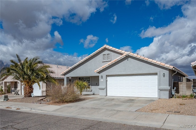 view of front of property featuring a garage, a tile roof, driveway, and stucco siding