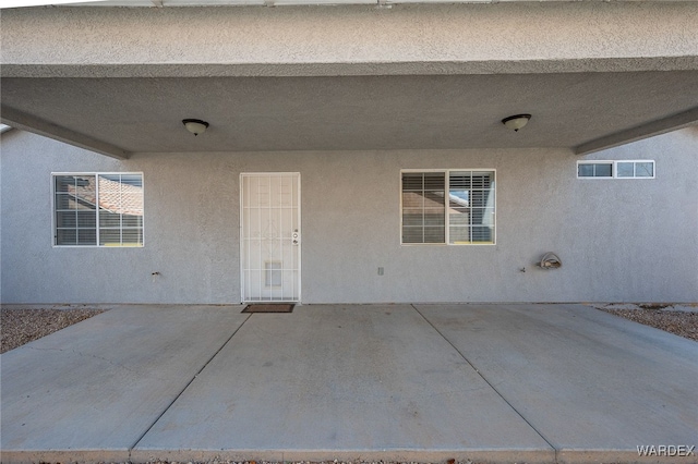 property entrance with a patio area and stucco siding