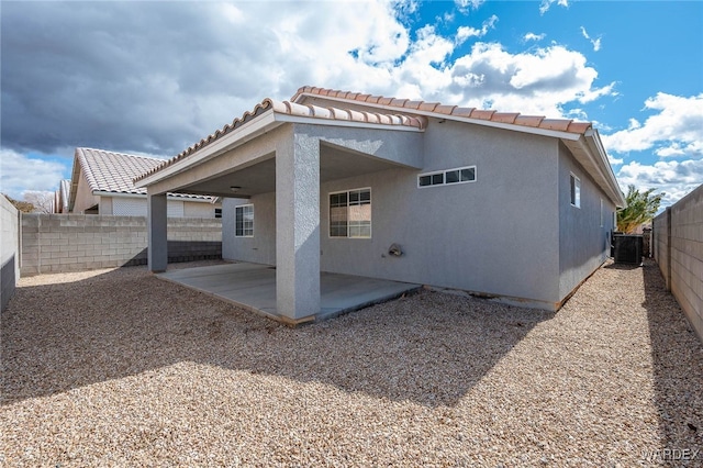 rear view of property featuring stucco siding, a fenced backyard, central AC, and a patio